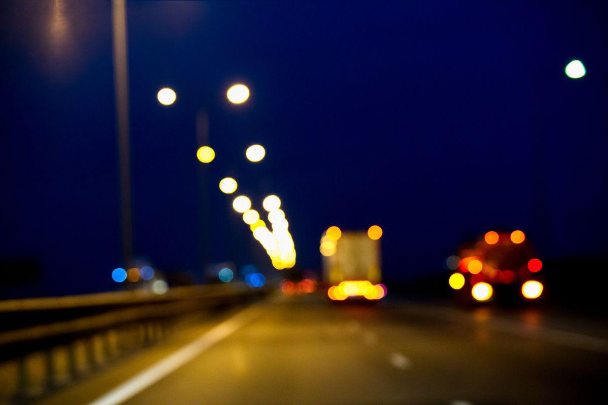 View through the windshield of a car on blurred ahead moving trucks. Night time. Motion blur. Low key. Defocused